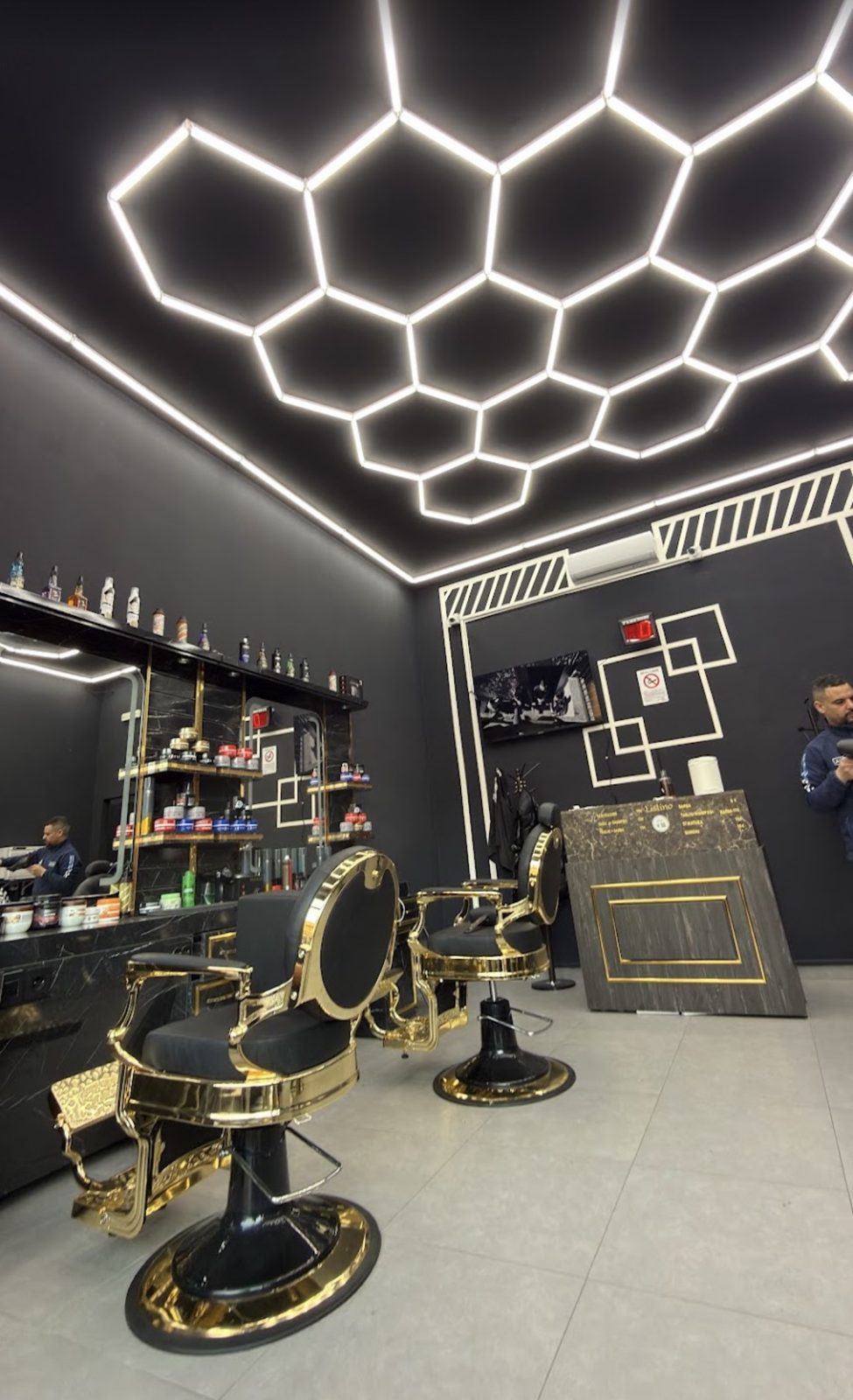 Interno del salone: soffitto con illuminazione LED a esagoni, poltrone nere e oro, banco in marmo nero