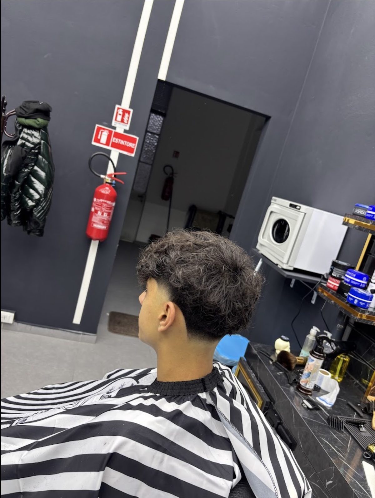 Capelli ricci sopra con taper basso sulla nuca